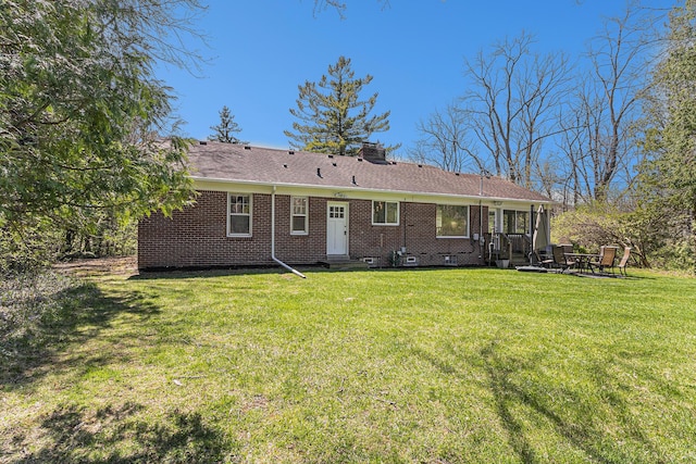 rear view of house featuring brick siding, a yard, a chimney, entry steps, and crawl space