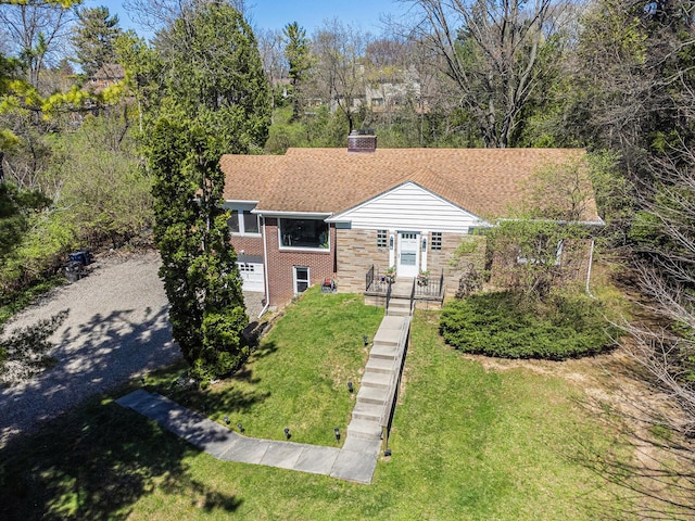 view of front of home featuring driveway, a chimney, roof with shingles, a front lawn, and brick siding