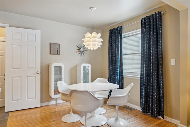 dining room featuring baseboards, visible vents, plenty of natural light, and hardwood / wood-style floors