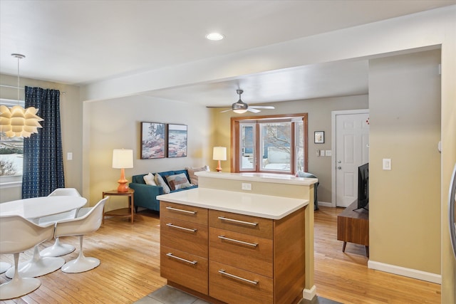 kitchen featuring light wood-style floors, brown cabinetry, light countertops, and open floor plan