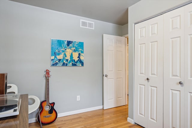 office space with light wood-type flooring, visible vents, and baseboards