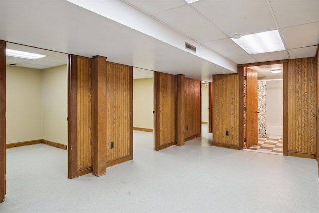 finished basement with a paneled ceiling, baseboards, and visible vents