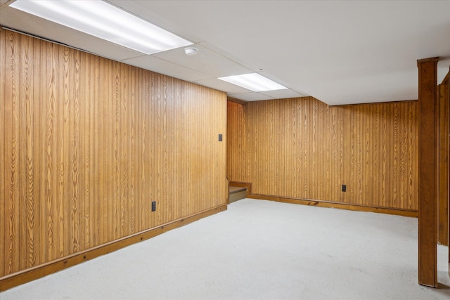 finished basement featuring carpet floors, wood walls, and a drop ceiling