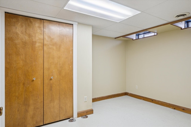 interior space featuring finished concrete floors, a drop ceiling, visible vents, and baseboards