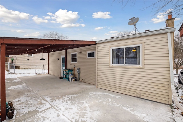 back of house with a carport, a chimney, and fence