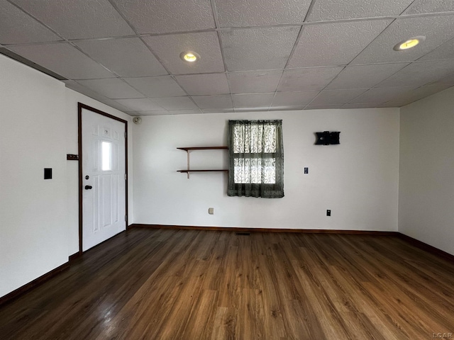 empty room featuring wood finished floors, a paneled ceiling, and baseboards