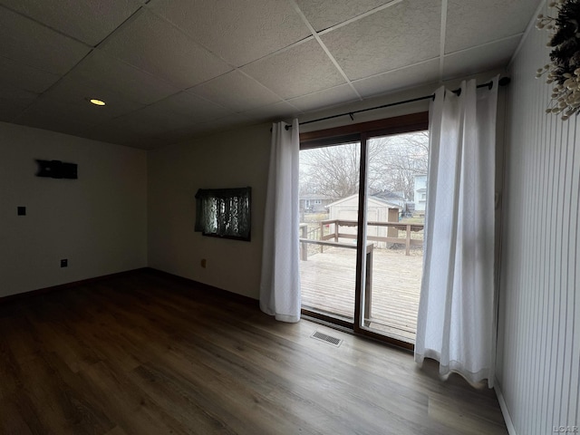 unfurnished room featuring dark wood-style floors, a paneled ceiling, visible vents, and baseboards