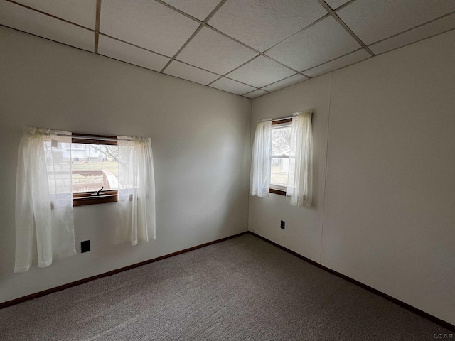 carpeted empty room with a paneled ceiling and baseboards