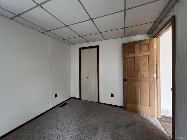 unfurnished bedroom featuring carpet floors, a drop ceiling, visible vents, and baseboards