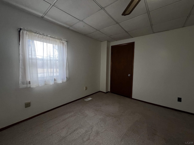 empty room featuring carpet floors, a drop ceiling, visible vents, and baseboards