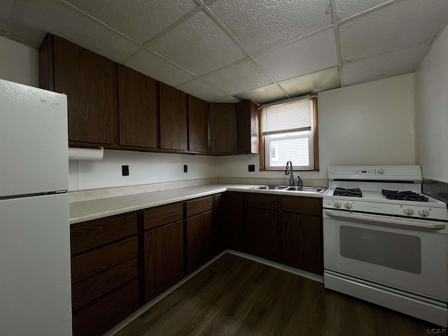 kitchen with dark wood-style floors, light countertops, a sink, dark brown cabinets, and white appliances