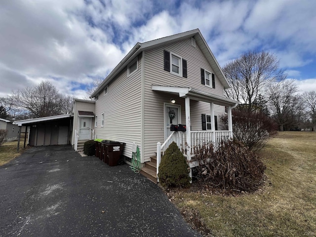 view of front of house with driveway, an attached carport, and a porch