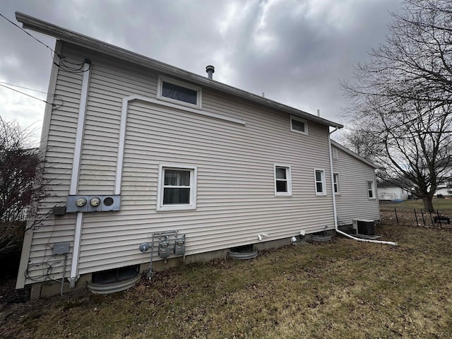 rear view of property with central air condition unit, fence, and a lawn