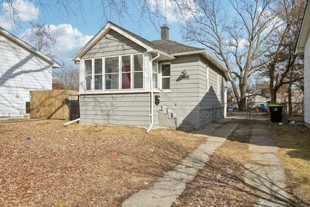 bungalow-style house with a gate, roof with shingles, fence, and a chimney