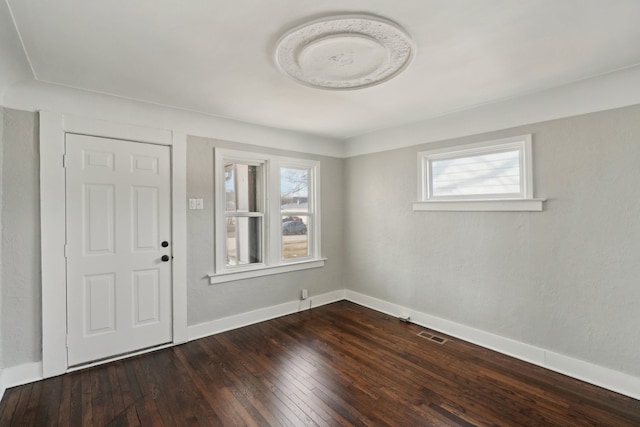 foyer entrance featuring baseboards, visible vents, and dark wood-style flooring