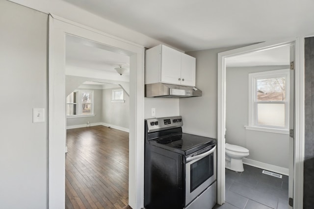 kitchen featuring under cabinet range hood, visible vents, baseboards, white cabinets, and stainless steel electric range