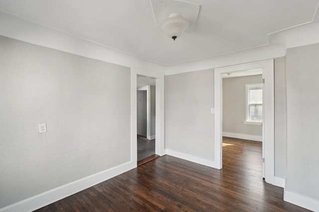 spare room with dark wood-style flooring and baseboards