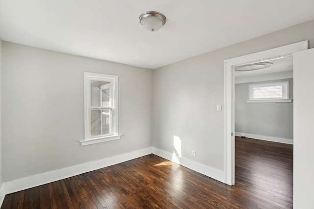 spare room with baseboards and dark wood-style flooring