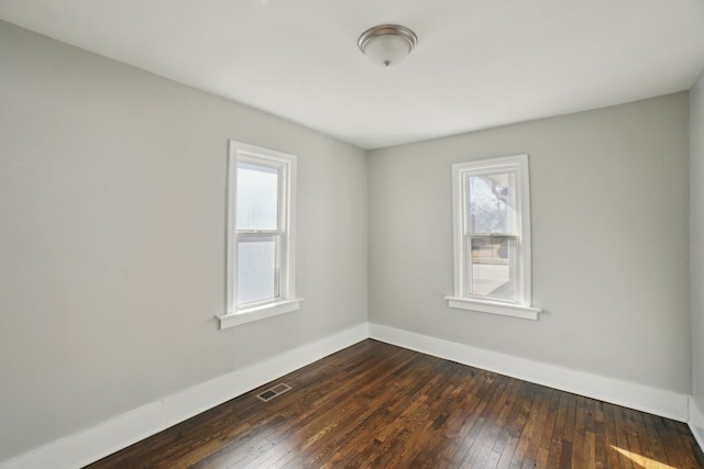 unfurnished room featuring dark wood-style floors, baseboards, and visible vents