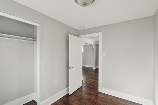 unfurnished bedroom featuring a closet, baseboards, and wood finished floors