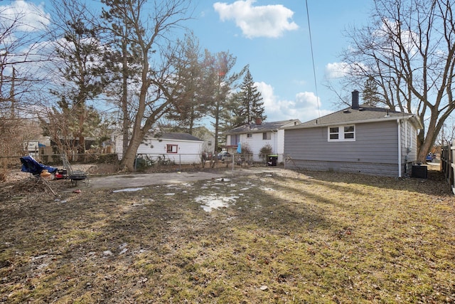 back of house featuring a lawn, a chimney, and fence