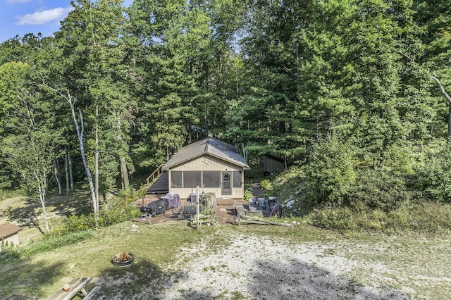 view of front of house featuring a forest view and an outdoor fire pit