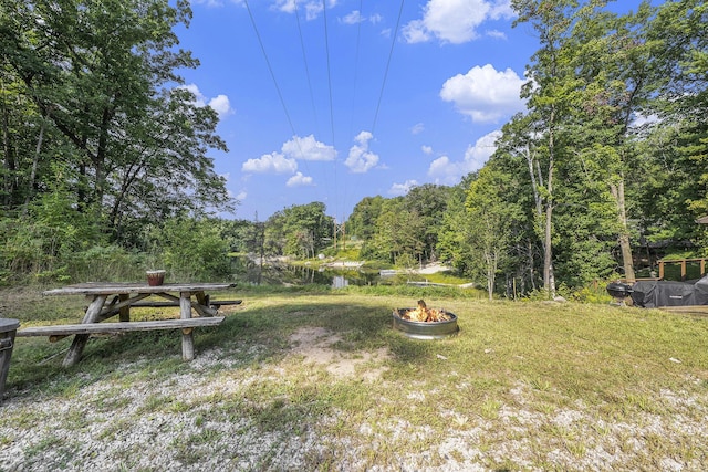 view of yard featuring a fire pit and a view of trees