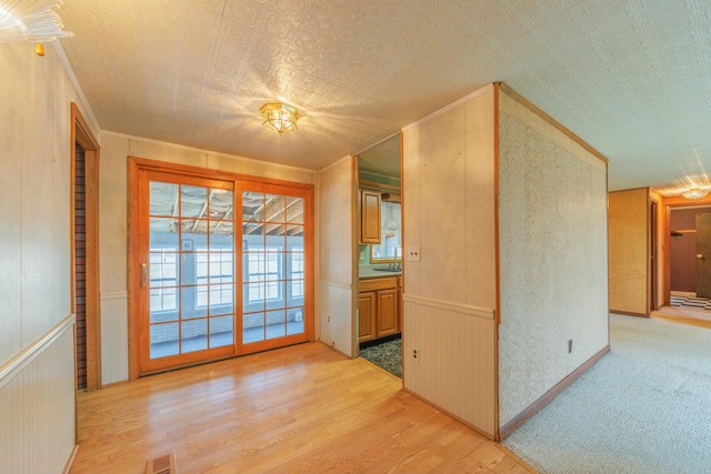 interior space with visible vents, light wood finished floors, an ornate ceiling, and crown molding