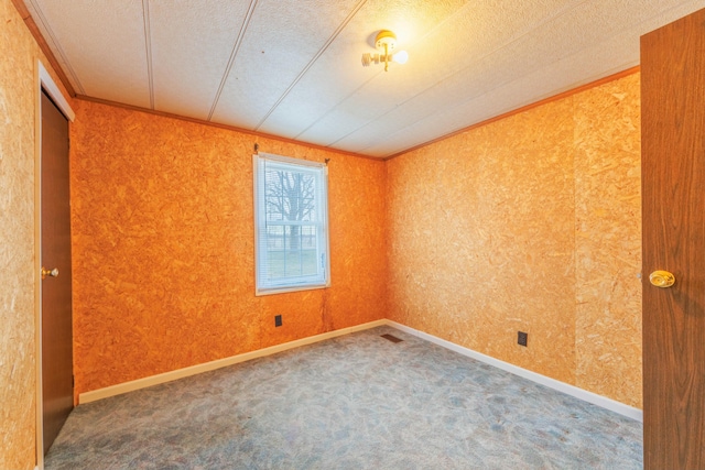 carpeted spare room featuring a textured ceiling, baseboards, and crown molding