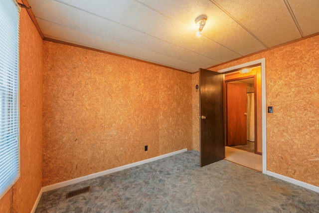 empty room with carpet, visible vents, and baseboards