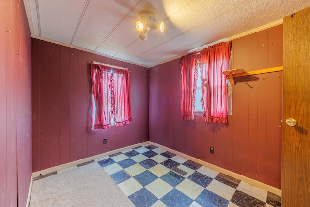 spare room with wooden walls, baseboards, and tile patterned floors