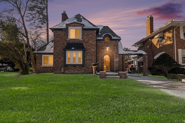 view of front of home featuring concrete driveway, brick siding, a yard, and a chimney