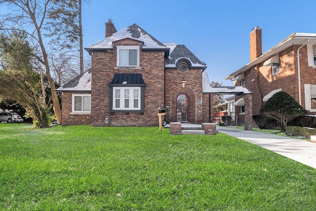 view of front of home featuring brick siding, a chimney, and a front lawn