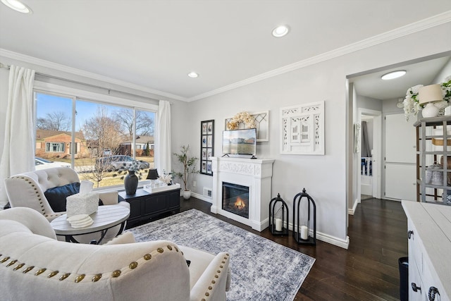 living area featuring a glass covered fireplace, dark wood finished floors, crown molding, and baseboards