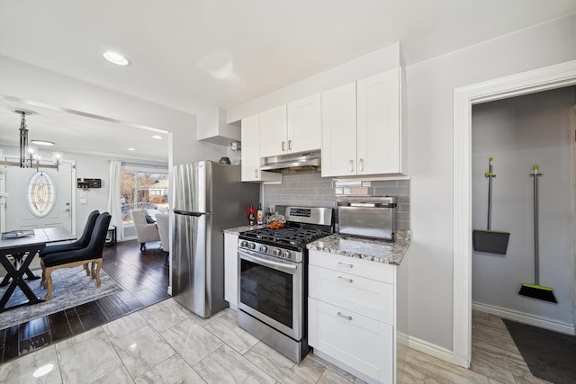 kitchen featuring tasteful backsplash, appliances with stainless steel finishes, light stone counters, under cabinet range hood, and white cabinetry