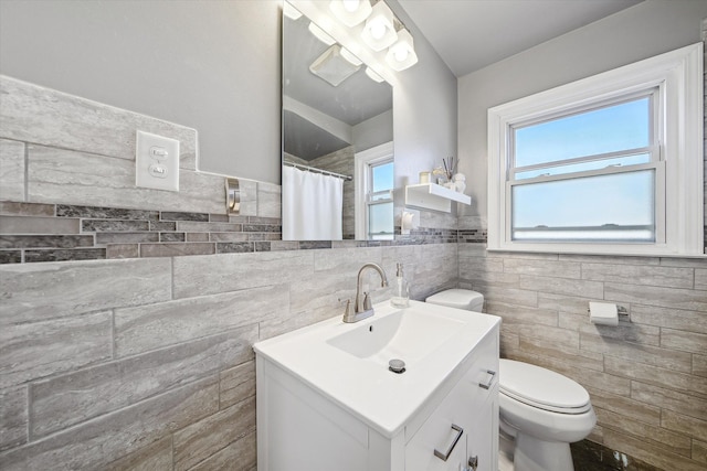 bathroom featuring curtained shower, vanity, toilet, and tile walls