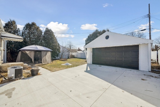 detached garage featuring fence and central AC unit