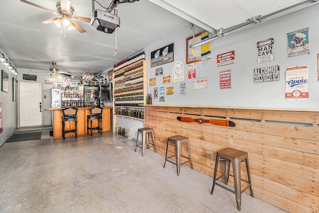 garage with wooden walls, a ceiling fan, and a garage door opener