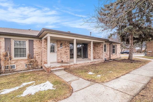 ranch-style home with covered porch, brick siding, and a front lawn