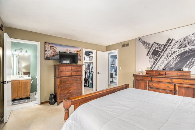 bedroom with ensuite bathroom, light carpet, visible vents, a spacious closet, and a closet