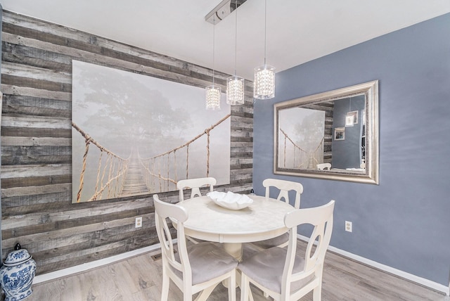 dining area featuring wooden walls, baseboards, and wood finished floors