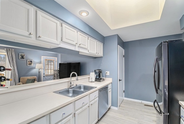 kitchen featuring stainless steel appliances, light countertops, white cabinetry, a sink, and baseboards