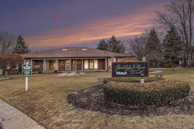 view of front of house featuring brick siding and a yard