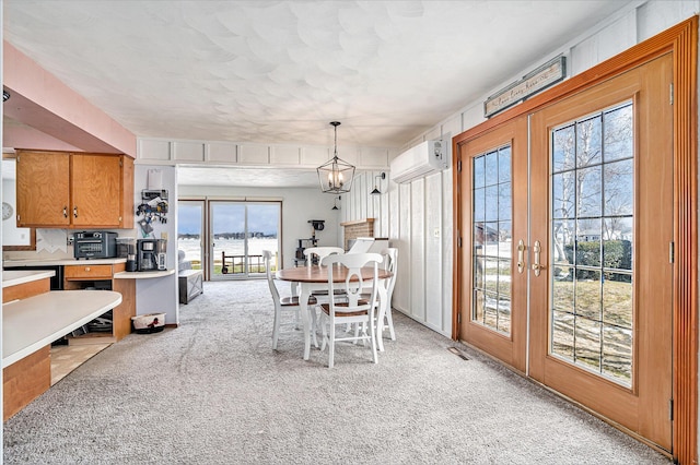 dining area with a notable chandelier, french doors, a wall mounted air conditioner, and light colored carpet