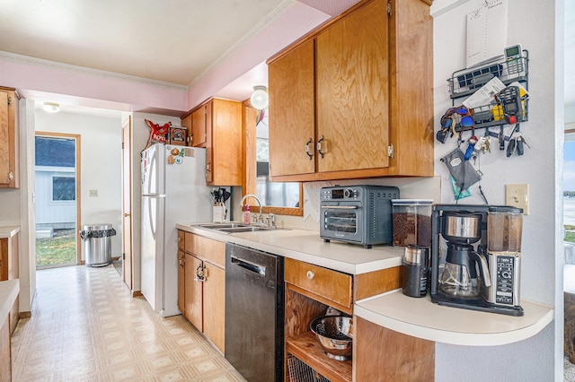 kitchen featuring dishwasher, freestanding refrigerator, light countertops, light floors, and a sink