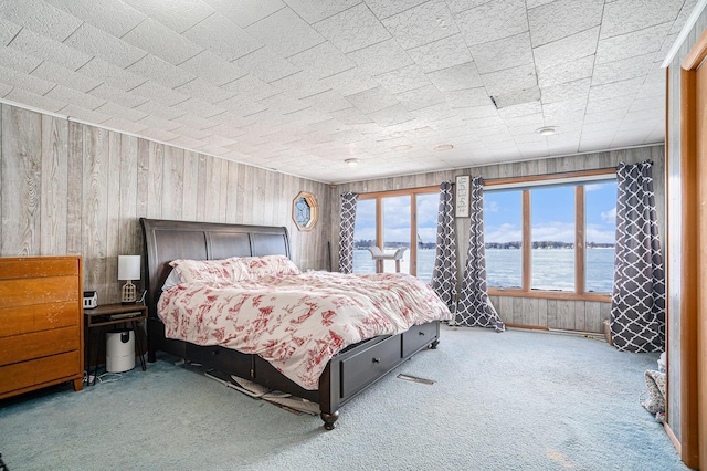 bedroom with a water view, wood walls, and carpet flooring