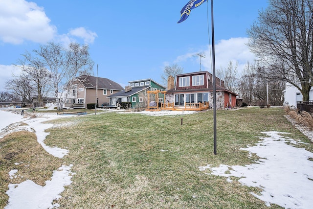 snow covered rear of property featuring a deck and a lawn