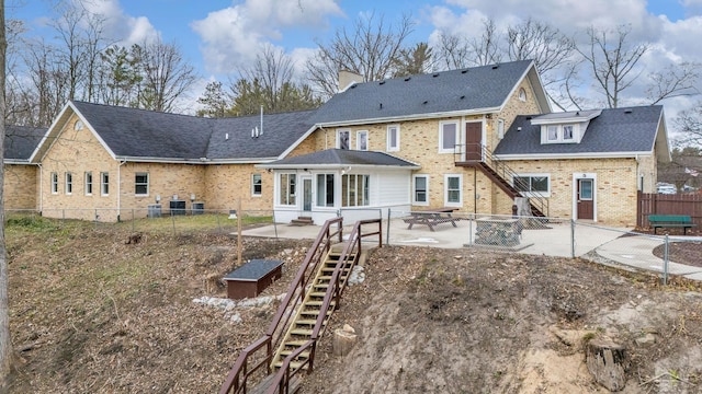 back of property with a fenced backyard, brick siding, a shingled roof, stairway, and a patio area