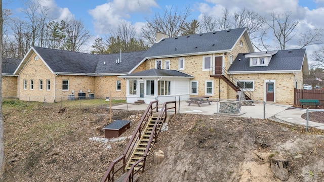 back of property featuring a patio area, brick siding, a fenced backyard, stairs, and a chimney