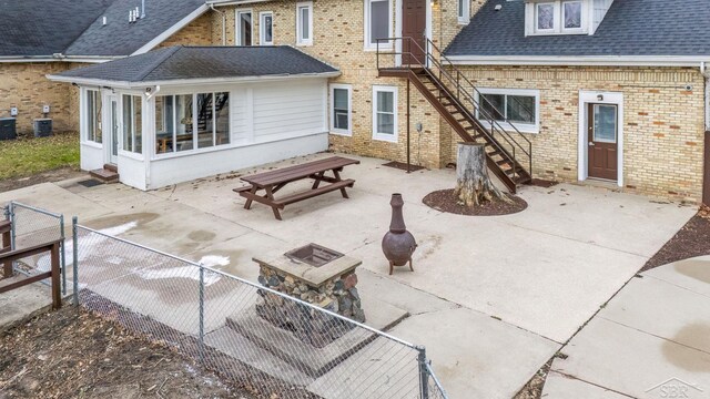 rear view of property with a patio, outdoor dining area, a sunroom, brick siding, and fence